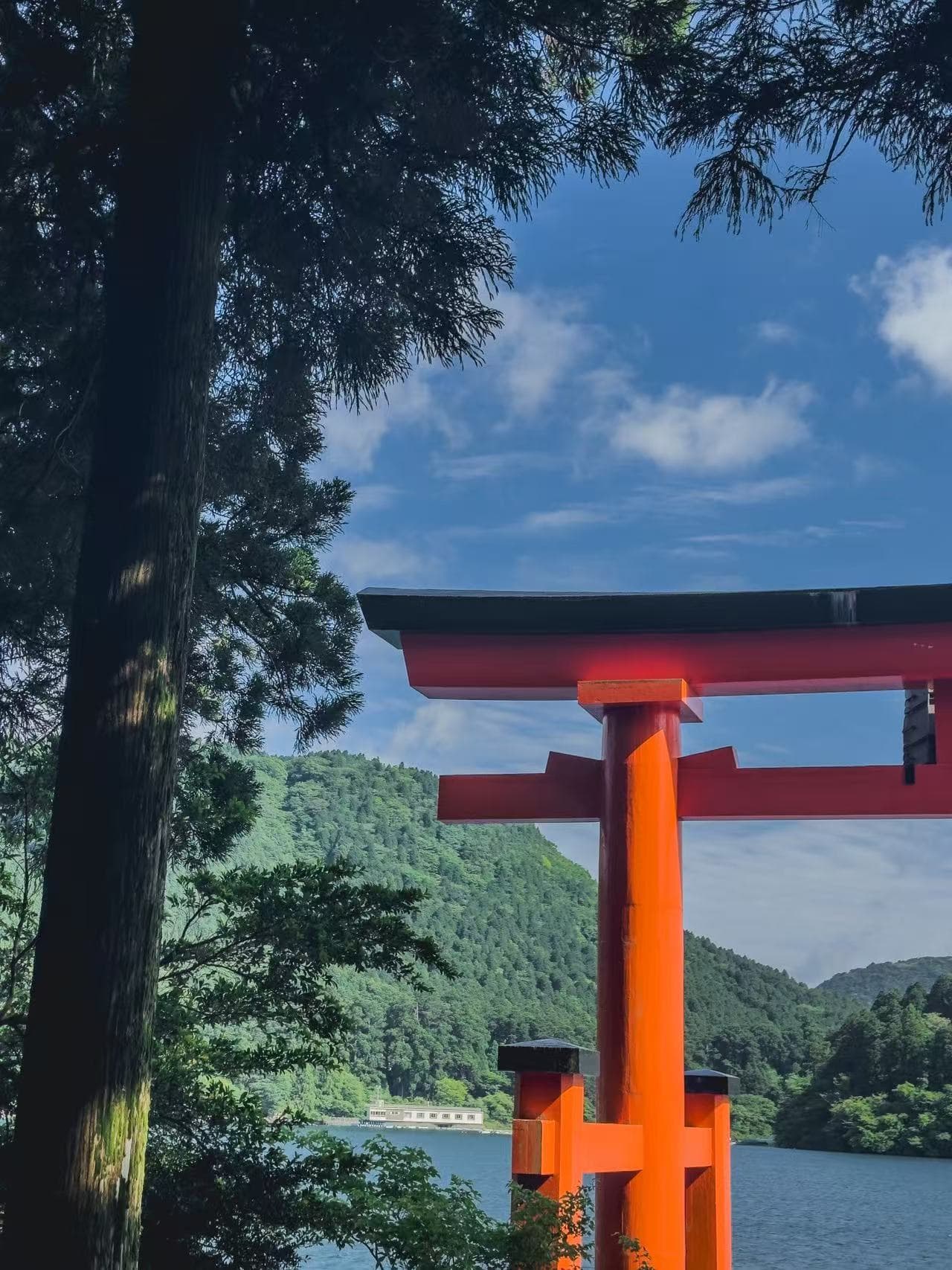 Red torii gate by a lake framed by trees